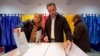 A man and a woman post their votes in the country's parliamentary elections, in Bucharest.