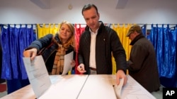 A man and a woman post their votes in the country's parliamentary elections, in Bucharest.