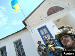 Soldiers pose for a photo with a Ukrainian national flag in the recently liberated village of Vasylenkove, in the Kharkiv region, on September 10.