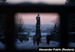 People walk to lay flowers at a monument erected in memory of Kuzbass miners to pay tribute to the miners and rescuers killed in the Listvyazhnaya tragedy on November 26, the day after the explosion.