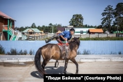 A man mounts his horse in Dadal. Many residents keep both a horse and a car.