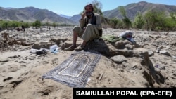 A man affected by floods sits next to a prayer mat as he waits for relief in the village of Borka in Baghlan Province in May.