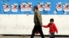 A man and a child walk past campaign posters of parliamentary candidates during the first day of the election campaign in Tehran on February 22.