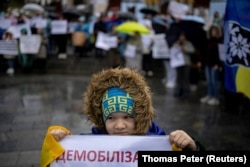 A child holds a placard during a protest in Kyiv last year by relatives of Ukrainian servicemen calling for legislation regulating the length of active military duty and the frequency of frontline rotation. (file photo)