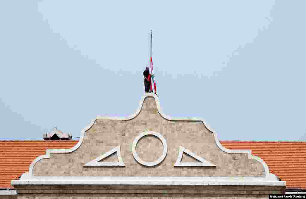 A man lowers the Lebanese national flag to half-mast outside the government palace, as caretaker Prime Minister Najib Mikati declared three days of mourning in Lebanon. &nbsp;