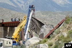 Railway officials inspect the remains of a collapsed railway bridge the morning after a blast by separatist militants at Kolpur in Bolan district, Balochistan Province, on August 27.