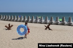 A girl walks in the sand near barriers set up against Russian military landing ships in Chornomorsk, Odesa region, in July.