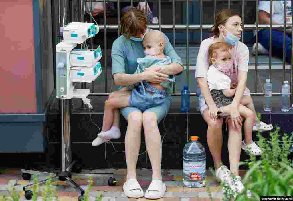 Women hold patients outside the damaged hospital. &nbsp;