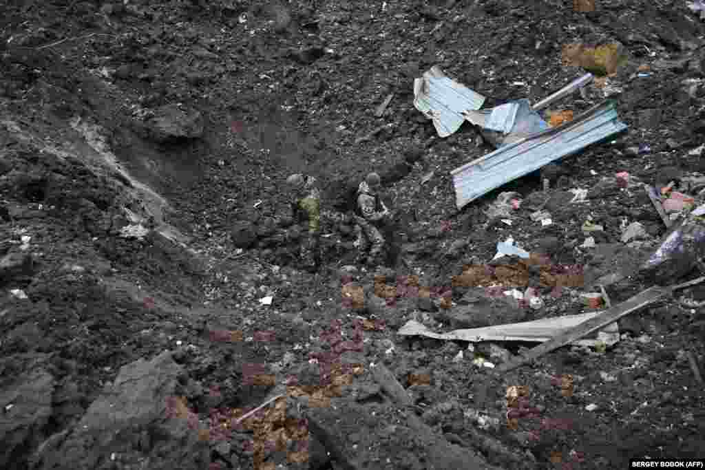 Several Ukrainian military experts in Kharkiv work in a crater outside a damaged residential building. The attacks come a day after Russia launched a record 90 Shahed-type drones across Ukraine during the early hours of the new year. Russian President Vladimir Putin said his country would &ldquo;intensify&rdquo; its attacks on its neighbor.