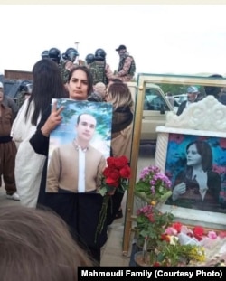 The wife of Fereydoun Mahmoudi, who was one of the victims of the protests in Iran, holds his picture.