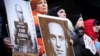 Demonstrators hold up pictures of Vladimir Putin and Aleksei Navalny at a rally near the Russian Consulate in New York following the announcement of Navalny's death on February 16.