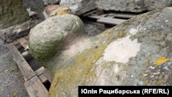 A stone sculpture bears apparent shrapnel damage.