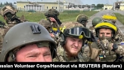 Members of the Russian Volunteer Corps pose for a picture atop an armored vehicle at the Graivoron border crossing in Kozinka, Belgorod region, Russia, on May 23.