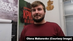 Kostyantyn Klyatskin with the poster of his documentary, titled Crimea As It Was, in the background.