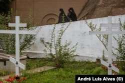 Monks walk by the graves of their brothers killed by shelling.