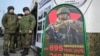 Russian soldiers stand near a mobile recruiting center with a board containing information about payments in Rostov-on-Don, Russia.