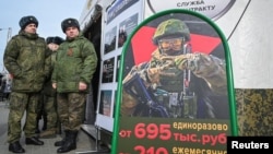 Russian soldiers stand near a mobile recruiting center with a board containing information about payments in Rostov-on-Don, Russia.