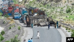 People look at a charred vehicle near a collapsed railway bridge a day after a blast by separatist Baloch Liberation Army militants at Kolpur in Bolan district, Balochistan Province, on August 27.