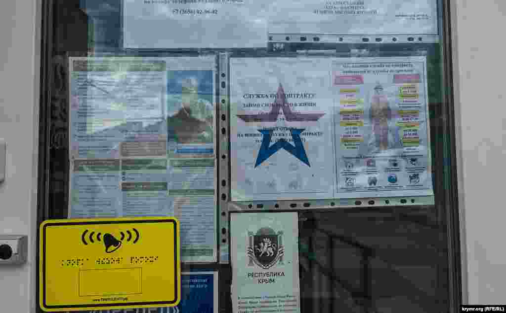 The Alushta bus station&#39;s doors are decorated with advertising seeking fresh recruits for the Russian military.