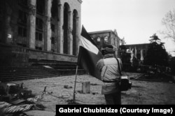 A visual journalist records the scene in front of the Georgian parliament.