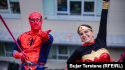 Volunteers dressed as Spiderman and Wonder Woman prepare to rappel down to the children waiting below.