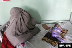 An Afghan woman sits next to a child suffering from malnutrition at a hospital in the southern city of Kandahar.