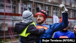 Berat Rexhepaj holds a child in his arms after rappelling from atop the clinic building.