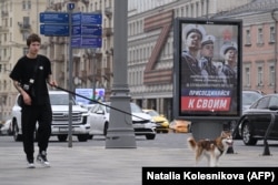 A young man in central Moscow walks dog past a poster promoting contract service in the Russian Army with the slogan "Join your people." (file photo)