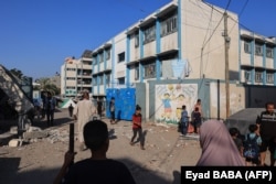 People walk past debris at a UN-run school after Israeli bombardment in Nuseirat in the central Gaza Strip in July. (file photo)