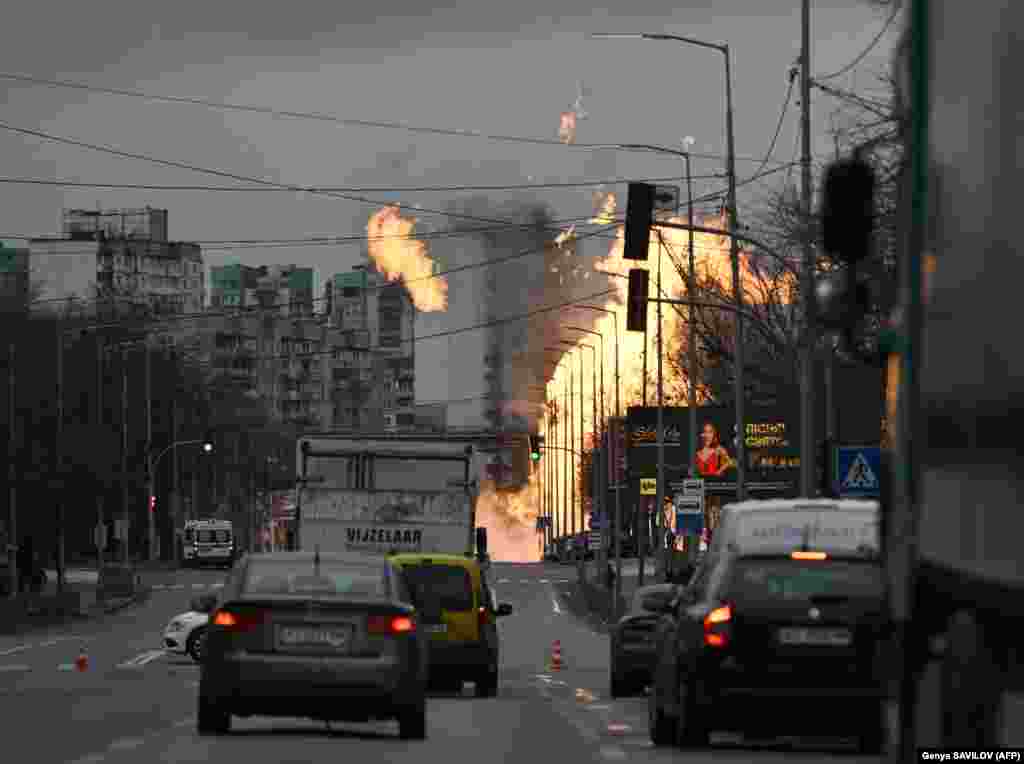 Motorists in the Ukrainian capital drive nearby as Ukrainian firefighters attempt to extinguish a fire after a missile strike. Air raid sirens blared for nearly four hours as many residents sought shelter in the city&#39;s subway.