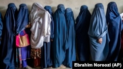 Afghan women wait to receive food rations distributed by a humanitarian aid group in Kabul.