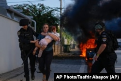 Police officers evacuate a woman and a child from Ashkelon on October 7.