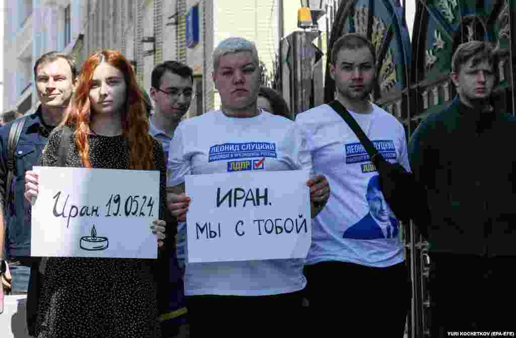 People holds signs reading &quot;Iran - 19.05.2024&quot; (left) and &quot;Iran we are with you&quot; outside the embassy in Moscow.