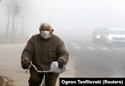 A man wearing a facemask rides his bicycle in Skopje on December 20.