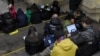 People check their devices for information in a Kyiv subway station during an air raid in March 2023.