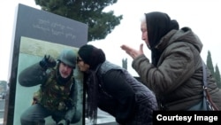 The wife and mother of Davit Ratiani mourn at his grave.