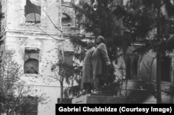 A statue of Georgian writers and national figures Ilia Chavchavadze and Akaki Tsereteli in front of a gutted building next to the Georgian parliament