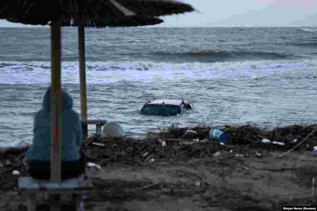 A woman looks at a car floating in the sea in the town of Tsarevo, on Bulgaria&#39;s Black Sea coast. on September 6. At least two men have died, and a search for a mother and child continues following torrential rains that caused widespread flooding in the region.