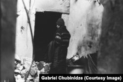 A woman looks through a destroyed apartment in central Tbilisi.