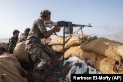 A Yemeni fighter backed by the Saudi-led coalition fires his weapon during clashes with Iran-backed Huthi rebels in Yemen in 2021.