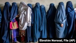 Afghan women wait to receive food rations distributed by a humanitarian aid group in Kabul in May 2023. 