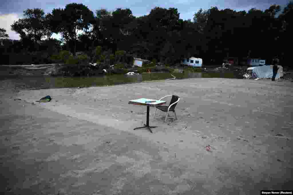 A table and chair near damaged caravans at a campsite. &nbsp;