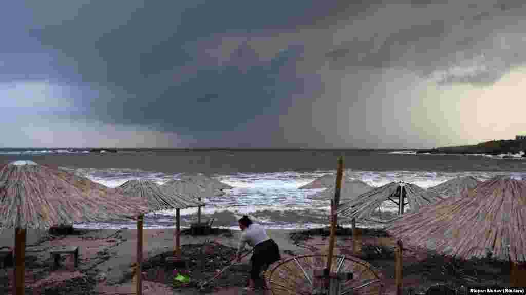 A woman cleans debris on the beach. &nbsp;