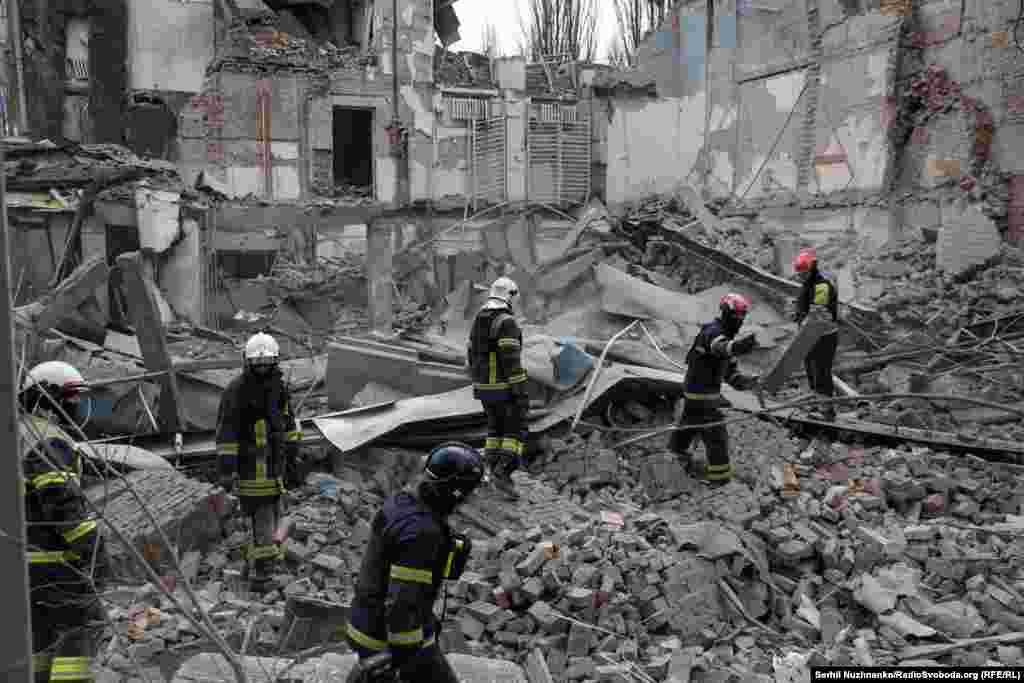 Firefighters pick through the rubble of a building in Kyiv destroyed by a falling Russian missile on March 25, 2024. &nbsp;