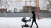 A man pushes a stroller near a residential building site in northern Moscow. (file photo)