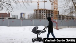 A man pushes a stroller near a residential building site in northern Moscow. (file photo)