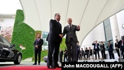 German Chancellor Olaf Scholz (right) shakes hands with the president of Tajikistan, Emomali Rahmon, in Berlin on September 29. Is that egg on the Tajik leader's car?