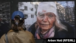 A woman looks at a photograph by Wolfgang Schwan of Ukrainian teacher Olena Kurilo, who was injured on February 24, 2022 -- the first day of the Russian invasion --  at the Ukraine: A War Crime exhibition, which opened in Pristina on April 29.