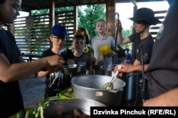 Children at the Call Of The Ravine camp line up to get their portion of cutlets, potatoes, zucchini, and cucumbers.