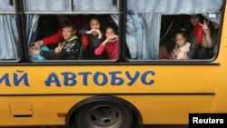 Children gesture as they are evacuated from the Russian-occupied town of Kupyansk town on the outskirts of Kharkiv, on May 30, 2022.